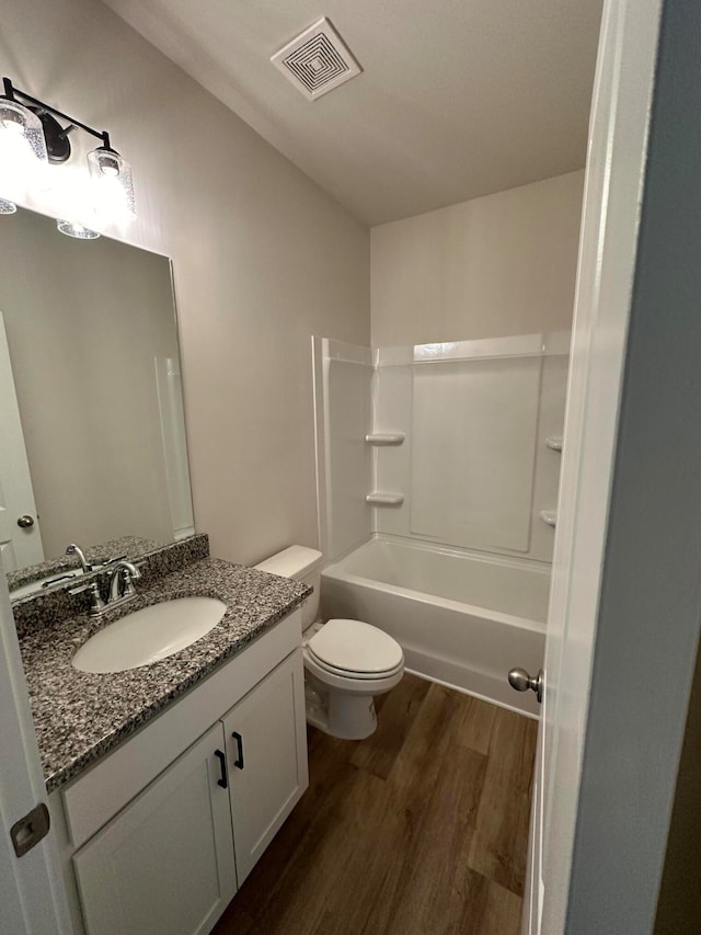 full bathroom with shower / washtub combination, vanity, wood-type flooring, and toilet