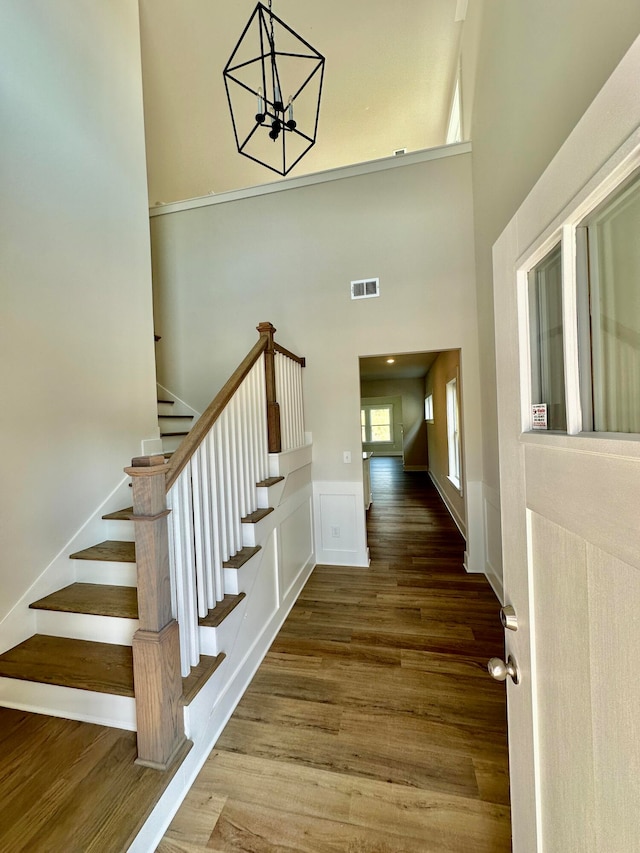 stairs featuring hardwood / wood-style flooring, a notable chandelier, and a towering ceiling