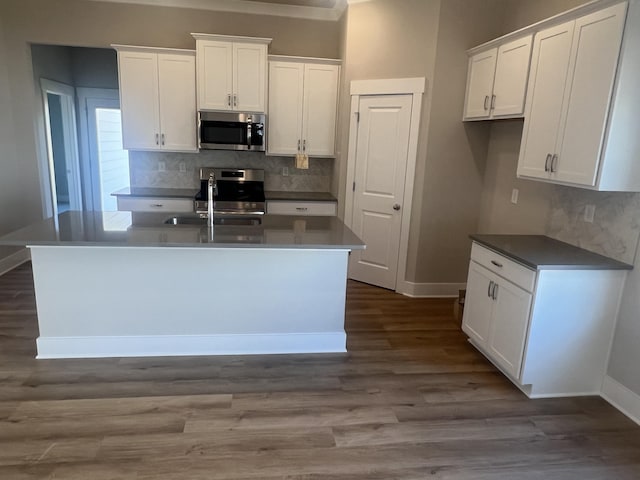 kitchen with white cabinetry, dark wood-type flooring, stainless steel appliances, and a center island with sink