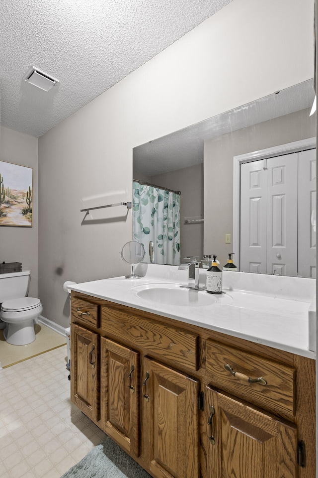 bathroom featuring vanity, a textured ceiling, and toilet