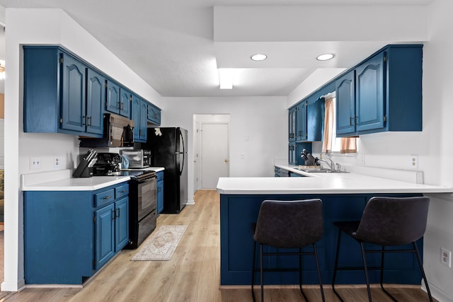 kitchen featuring black appliances, sink, light wood-type flooring, and blue cabinetry