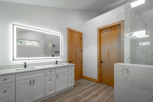 bathroom with tiled shower, hardwood / wood-style floors, and vanity