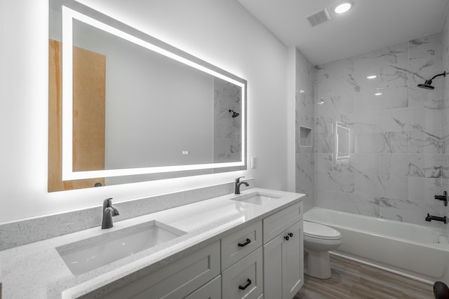 full bathroom with hardwood / wood-style floors, vanity, toilet, and tiled shower / bath