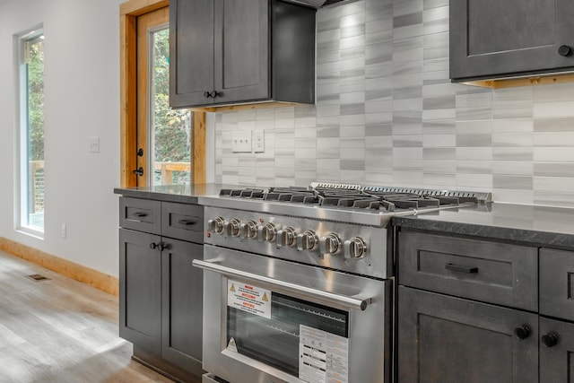 kitchen with backsplash, gray cabinetry, stainless steel stove, and light hardwood / wood-style floors