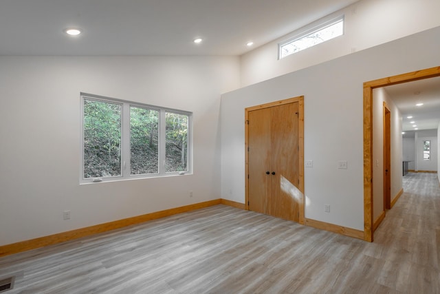 spare room featuring high vaulted ceiling and light hardwood / wood-style flooring