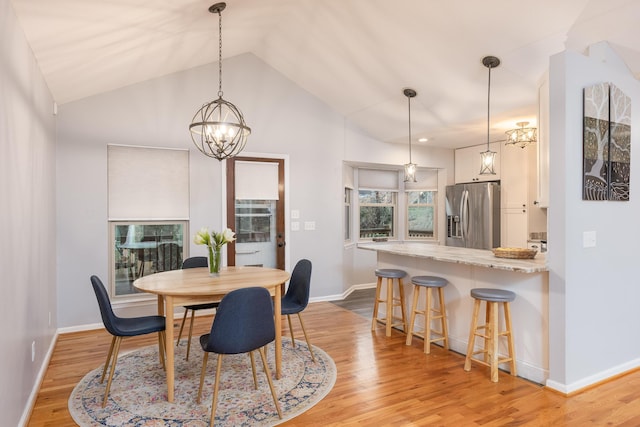 dining room with an inviting chandelier, light hardwood / wood-style floors, and vaulted ceiling