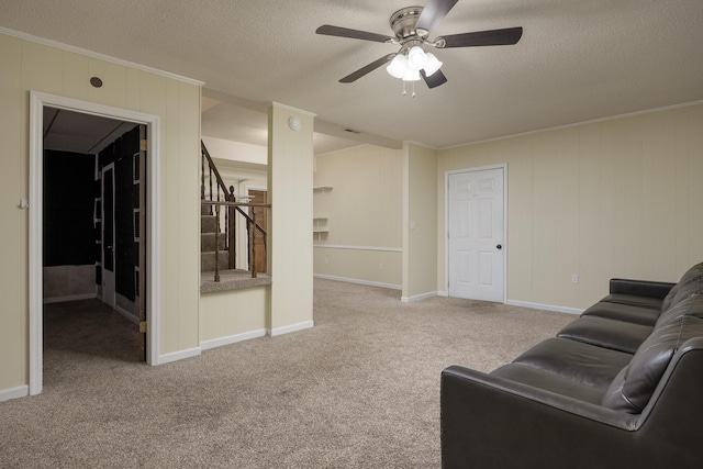 carpeted living room with ceiling fan, a textured ceiling, and ornamental molding