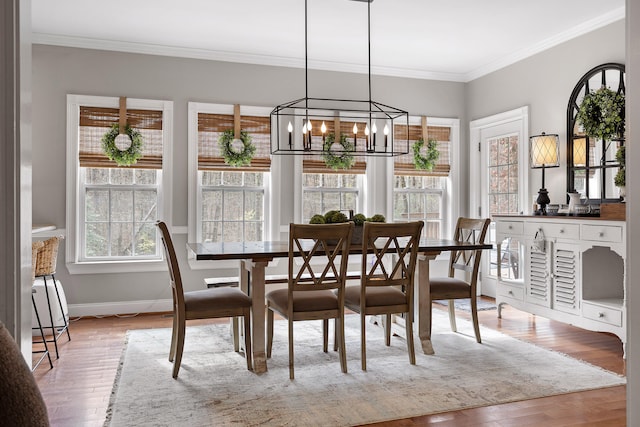 dining space featuring a notable chandelier, light hardwood / wood-style flooring, and crown molding