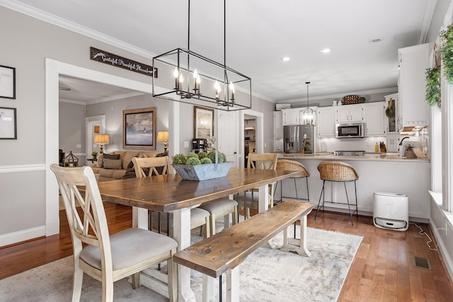 dining area with hardwood / wood-style flooring and crown molding