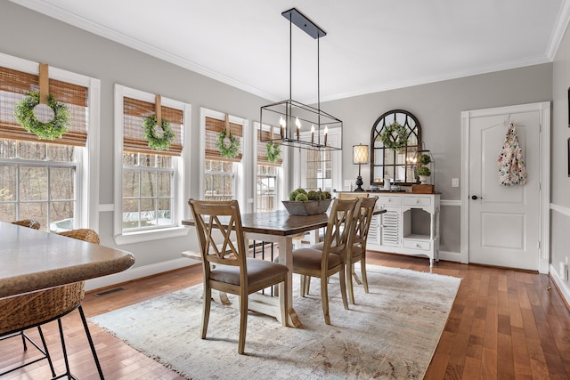 dining room featuring crown molding, hardwood / wood-style flooring, and an inviting chandelier