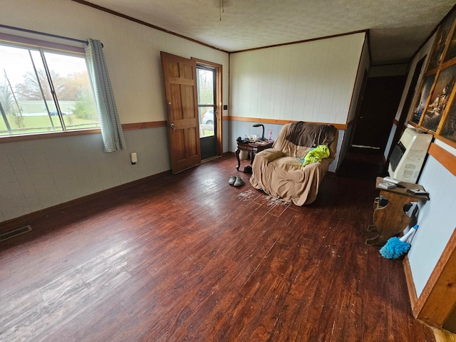 living area with a textured ceiling, dark hardwood / wood-style flooring, and ornamental molding