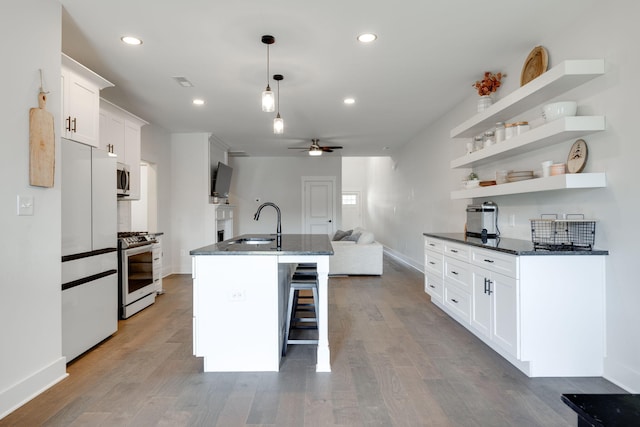 kitchen featuring appliances with stainless steel finishes, ceiling fan, a center island with sink, light hardwood / wood-style floors, and white cabinetry