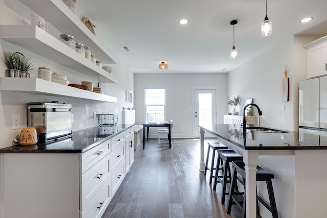 kitchen with sink, white refrigerator, decorative light fixtures, white cabinets, and dark hardwood / wood-style floors