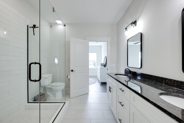 bathroom featuring toilet, vanity, tile patterned floors, and a shower with door