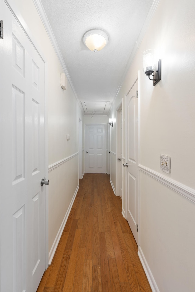 hall with a textured ceiling, hardwood / wood-style flooring, and crown molding