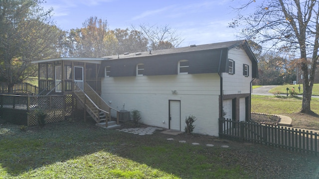 rear view of house featuring a yard, a garage, a wooden deck, and a sunroom