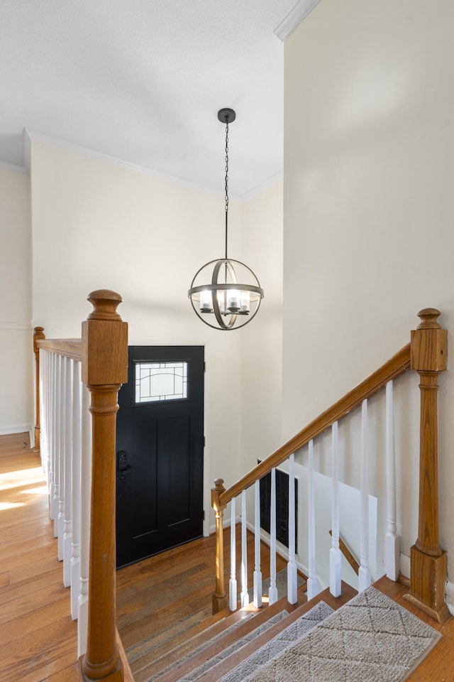 foyer entrance with crown molding, a chandelier, and hardwood / wood-style flooring