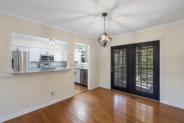 entryway featuring sink, french doors, hardwood / wood-style floors, a chandelier, and ornamental molding