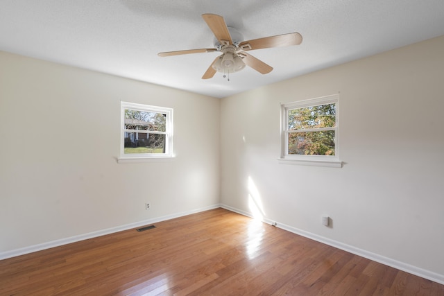 unfurnished room featuring ceiling fan, hardwood / wood-style floors, a healthy amount of sunlight, and a textured ceiling