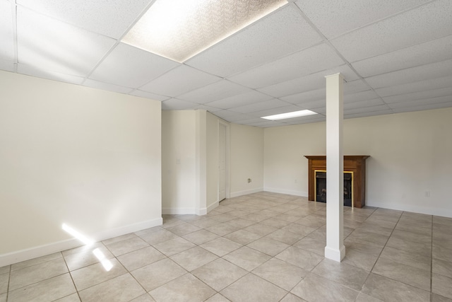 basement featuring a drop ceiling and light tile patterned floors