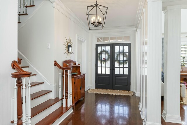 entrance foyer featuring dark hardwood / wood-style flooring, crown molding, french doors, and an inviting chandelier