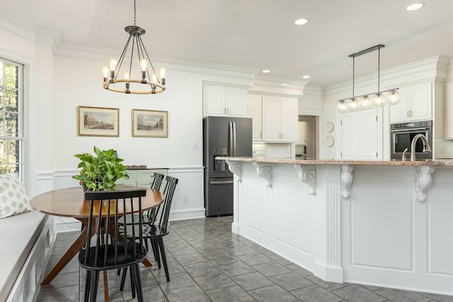 kitchen featuring a breakfast bar area, hanging light fixtures, white cabinets, and stainless steel appliances