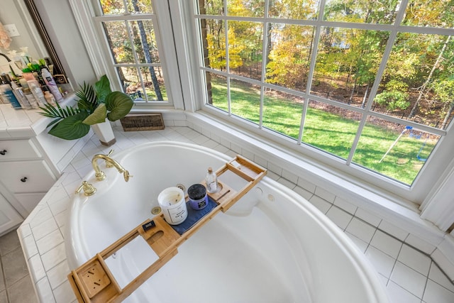 bathroom with a tub to relax in, a wealth of natural light, and tile patterned floors