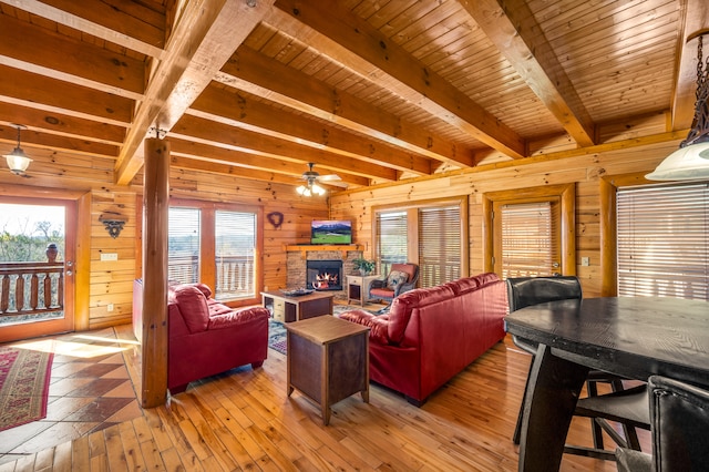 living room featuring wooden walls, light hardwood / wood-style flooring, ceiling fan, beamed ceiling, and wood ceiling