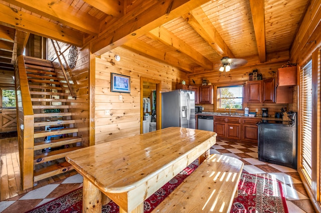 kitchen featuring beamed ceiling, stainless steel appliances, wooden walls, and wooden ceiling