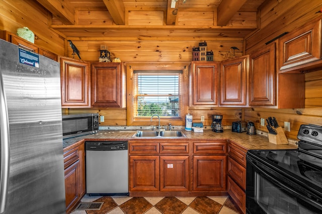 kitchen featuring beam ceiling, wooden walls, sink, and appliances with stainless steel finishes