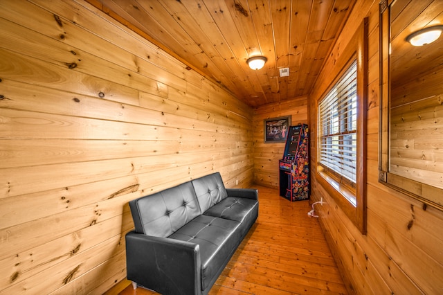 sitting room with wooden walls, wooden ceiling, and hardwood / wood-style flooring