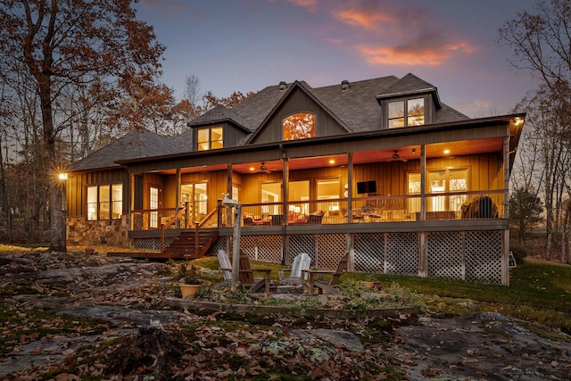 back house at dusk featuring ceiling fan and a fire pit