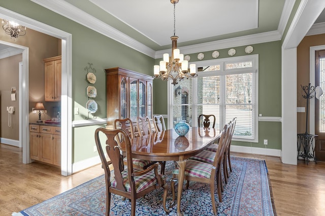 dining space featuring light hardwood / wood-style flooring, a notable chandelier, and crown molding