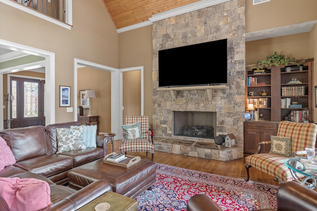 living room featuring a stone fireplace, high vaulted ceiling, wood-type flooring, and ornamental molding