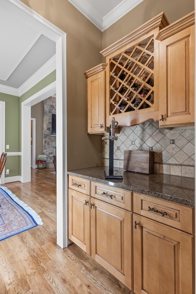 kitchen featuring light brown cabinets, backsplash, light hardwood / wood-style flooring, and ornamental molding