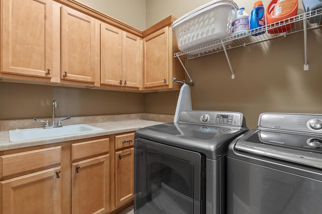 clothes washing area with cabinets, separate washer and dryer, and sink