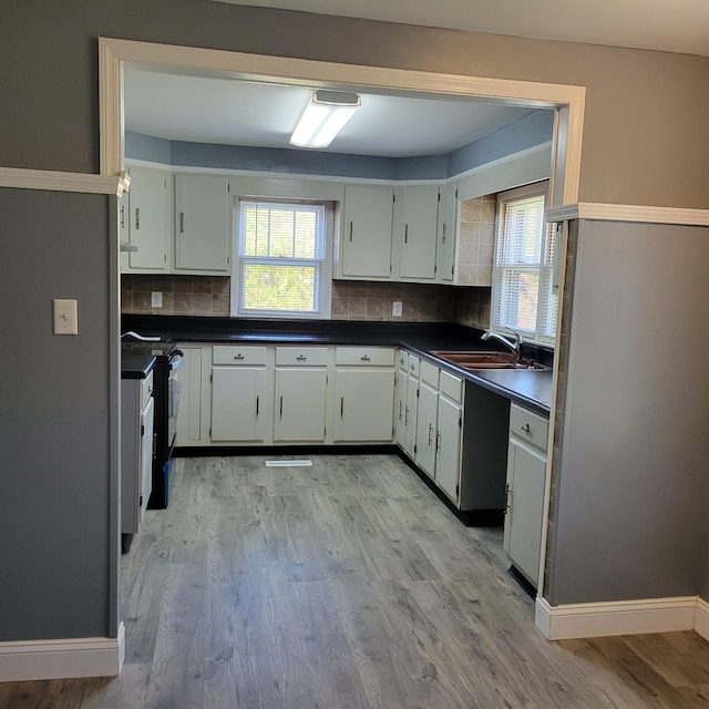 kitchen with white cabinets, backsplash, light hardwood / wood-style flooring, and sink