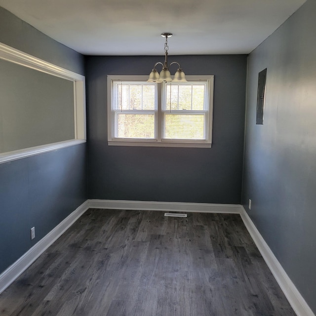 unfurnished dining area with electric panel, dark wood-type flooring, and a notable chandelier