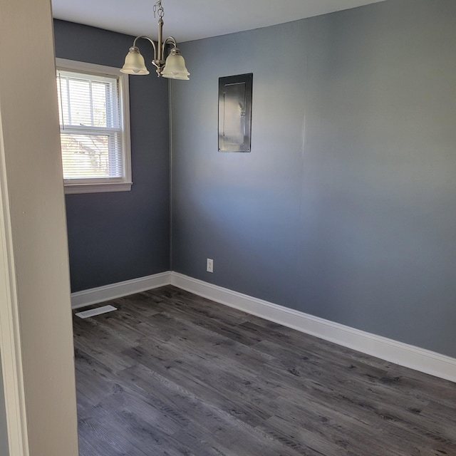 spare room featuring a chandelier, electric panel, and dark wood-type flooring