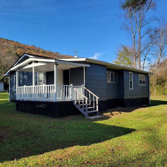 rear view of property featuring a lawn and a porch