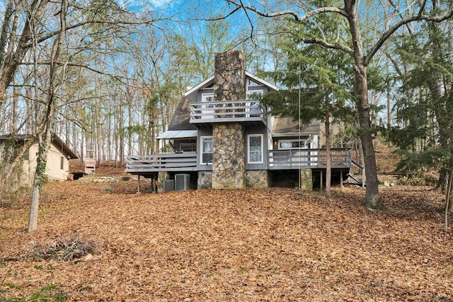 exterior space featuring a balcony, central AC unit, and a wooden deck