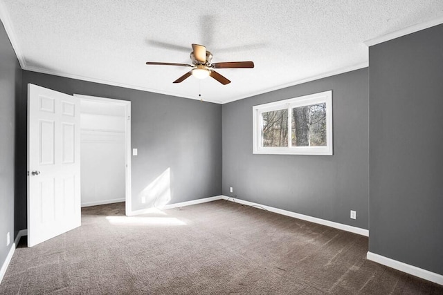 interior space with ceiling fan, dark carpet, ornamental molding, and a textured ceiling