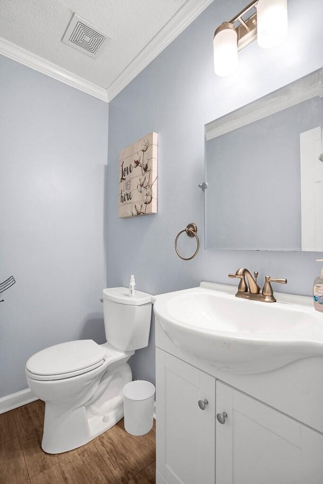 bathroom with vanity, hardwood / wood-style flooring, toilet, ornamental molding, and a textured ceiling