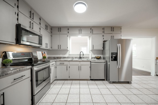 kitchen with appliances with stainless steel finishes, light tile patterned floors, ornamental molding, and sink