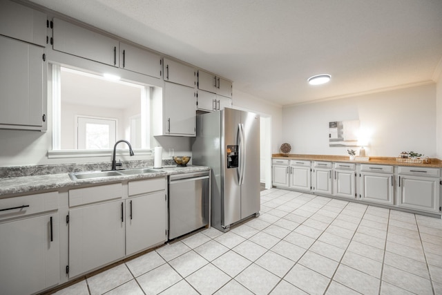 kitchen featuring sink, light tile patterned flooring, ornamental molding, and appliances with stainless steel finishes