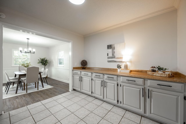 9100 Coventry Ln, Chattanooga, TN 37416 - kitchen with crown molding, a chandelier, white cabinetry, light wood-style floors, and decorative light fixtures