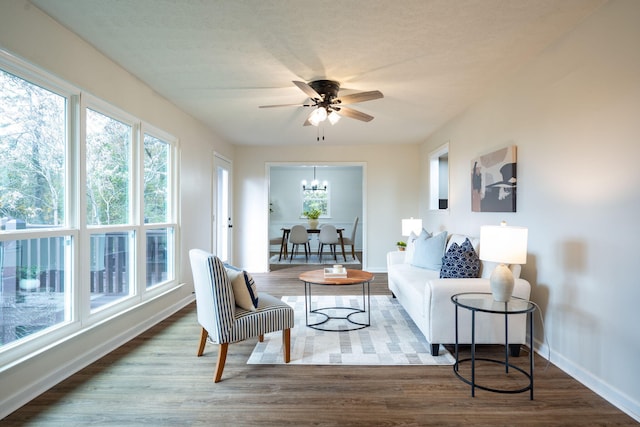 living room featuring ceiling fan with notable chandelier and hardwood / wood-style flooring