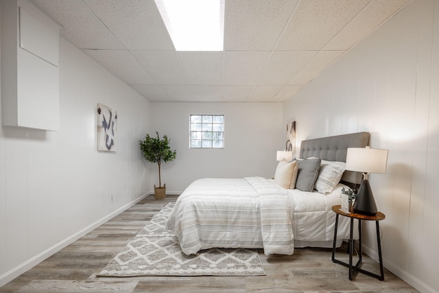 bedroom featuring light hardwood / wood-style flooring and a drop ceiling