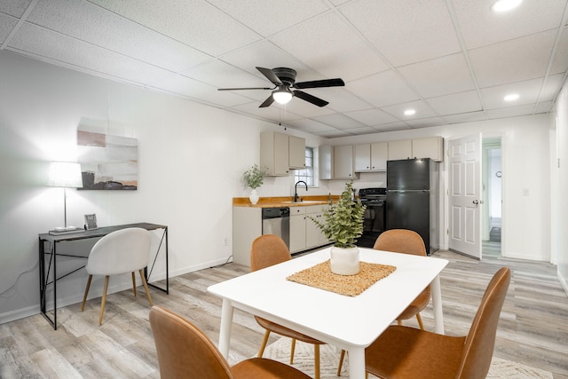 dining space featuring a paneled ceiling, ceiling fan, sink, and light hardwood / wood-style floors