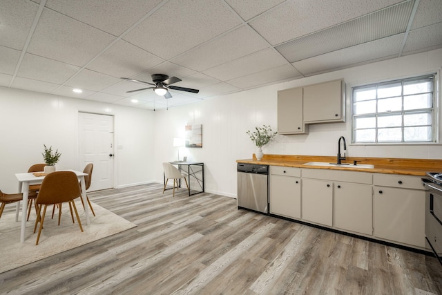 kitchen with butcher block counters, ceiling fan, sink, stainless steel dishwasher, and light wood-type flooring